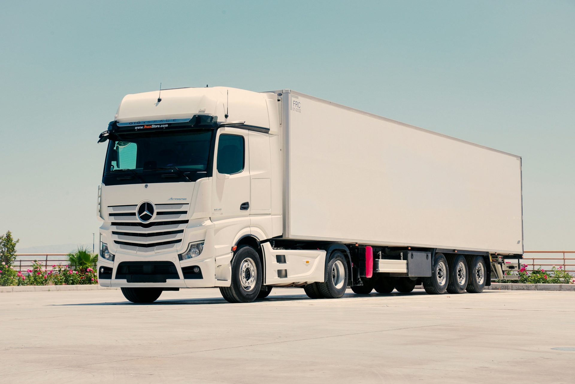 A white mercedes-benz semi-truck with a trailer parked outdoors.